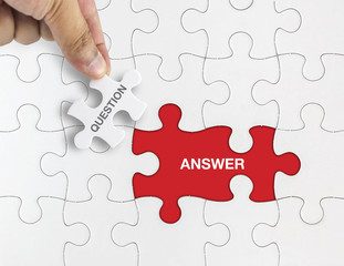 Fototapeta premium Hand holding piece of jigsaw puzzle with word QUESTION ANSWER.