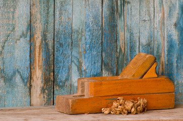 Old wooden plane and chips on a background of the old wall