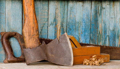 Carpenter tools: ax, planer and saw on the background of the old wooden walls