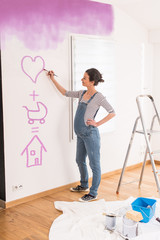 Pregnant woman painting the bedroom walls of her future baby