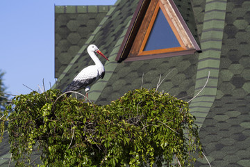 Nest of storks against the blue sky and house. Sculptural composition