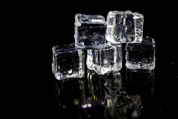 ice cubes reflection on black table background.