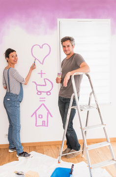  a pregnant woman and his husband painting the baby's bedroom