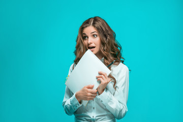 Surprised young business woman with pen and tablet for notes on blue background