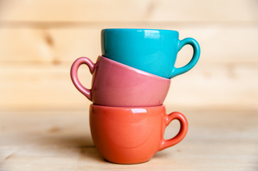 Colored cups on the wooden background