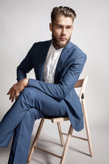 Young handsome man in a suit sitting on a chair