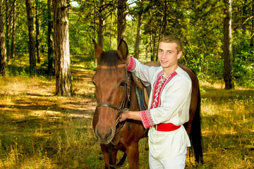 young Ukrainian with a horse in the forest