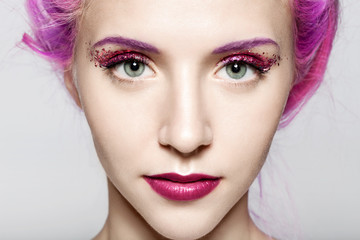 Close-up of a woman's face with a shiny trendy makeup in violet tones with sparkles