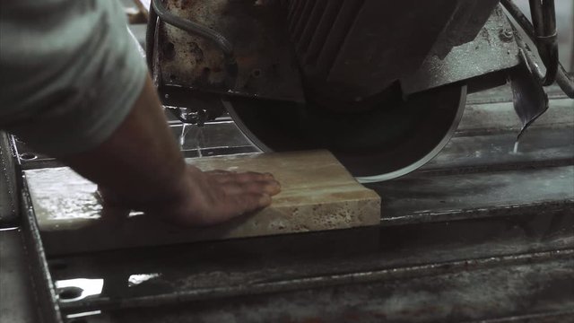 Worker uses saw machine for cutting marble stone, close up