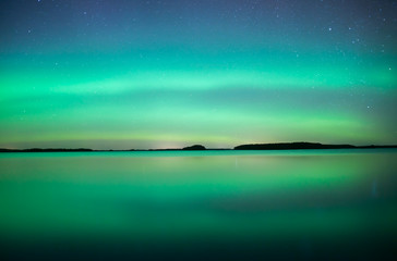 Northern lights dancing over calm lake in Sweden