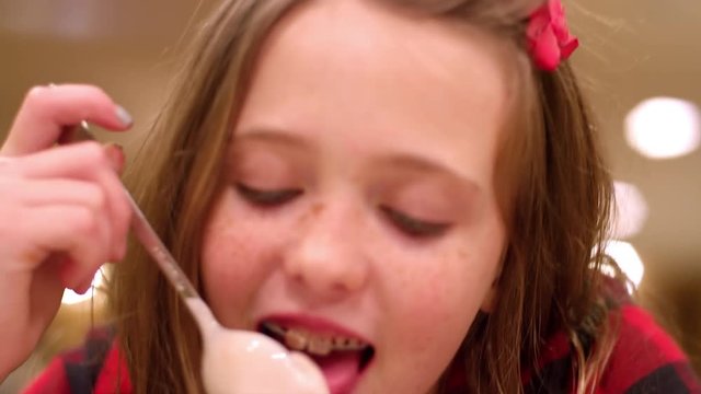 Close up, young girl with braces eating ice cream, slow motion