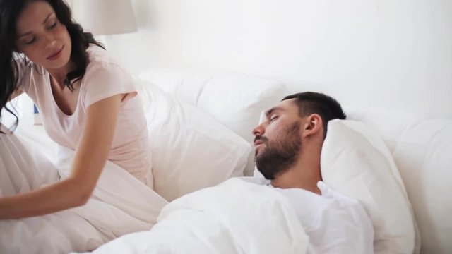 angry woman waking man sleeping in bed