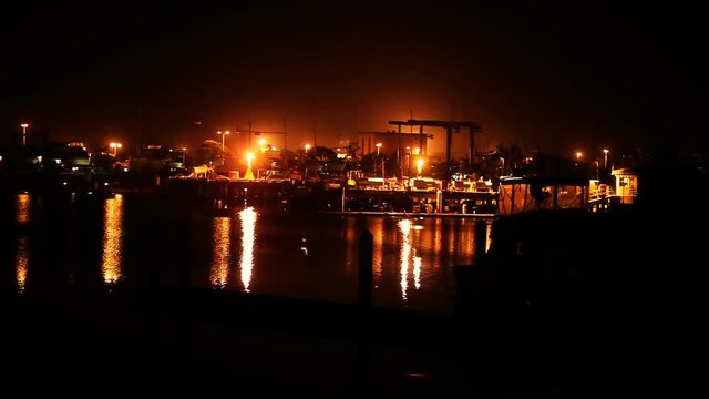 A stationary shot of an industrial fishing dock at night.