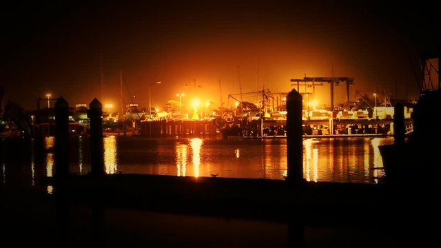 A stationary shot of an industrial fishing dock at night.