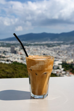 Ice frappe coffee and view of town of Athens for background