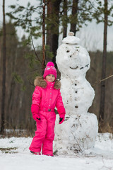 Girl next to a snowman winter day in the forest