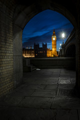 Brick tunnel overlooking Big Ben and the Houses of Parliament at night from across the river Thames...
