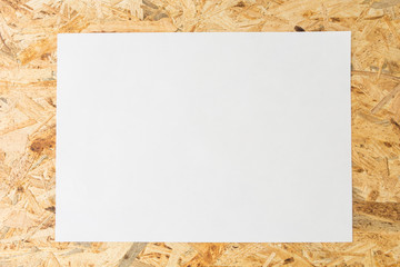 Blank white sheet of paper, on flakeboard