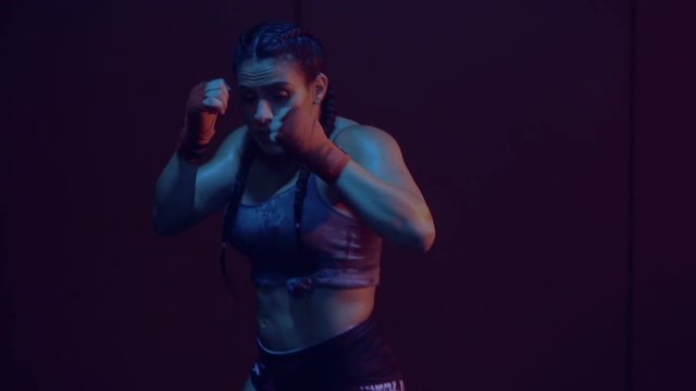 Closeup of brunette strong sexy woman sweating doing air punching training over red dark wall at the thai box gym - video in slow motion. Fitness, sport, training and people concept