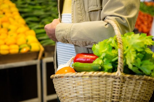 Man holding a basket of vegetables in super market