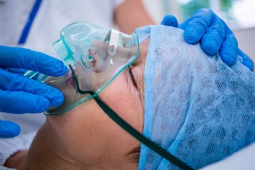 Patient wearing oxygen mask lying on hospital bed