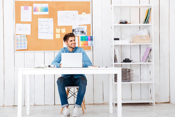 Happy young handsome businessman using laptop computer in office