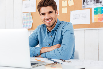 Happy businessman sitting at the table with arms folded