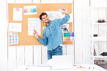 Businessman making selfie while standing in front of task board