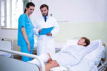 Doctor and nurse discussing over patient s leg