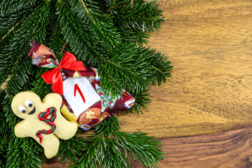 ein Weihnachtssäckchen und ein Plätzchenmann liegen auf Tannenzweigen