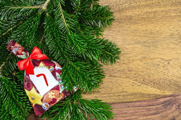 ein Weihnachtssäckchen mit roter Schleife liegen auf Tannenzweigen