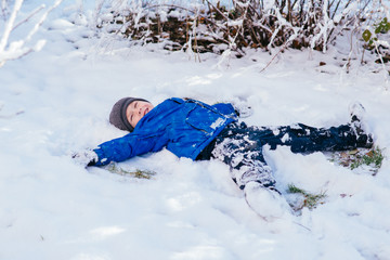 Fototapeta na wymiar мальчик лежит в снегу на спине
