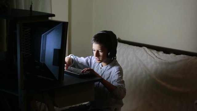 Teen boy plays games on the computer at night. Online Games