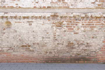 Broken old bricklaying wall from red white bricks with damaged plaster and road pavement background texture