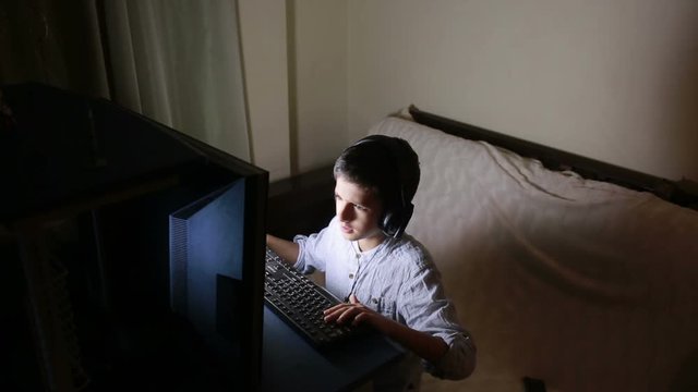 Teen boy plays games on the computer at night. Online Games