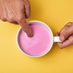 man soaking his finger in a pink milkshake