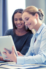 smiling businesswomen with tablet pc in office