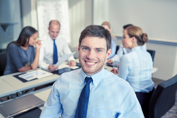 group of smiling businesspeople meeting in office