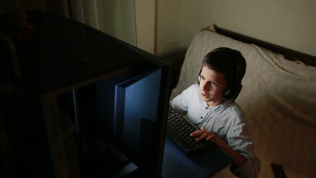 Teen boy plays games on the computer at night. Online Games