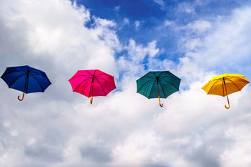 Fototapeta na wymiar Blue Umbrella, Red Umbrella, Green Umbrella and Yellow Umbrella floating in the Air under blue sky and clouds