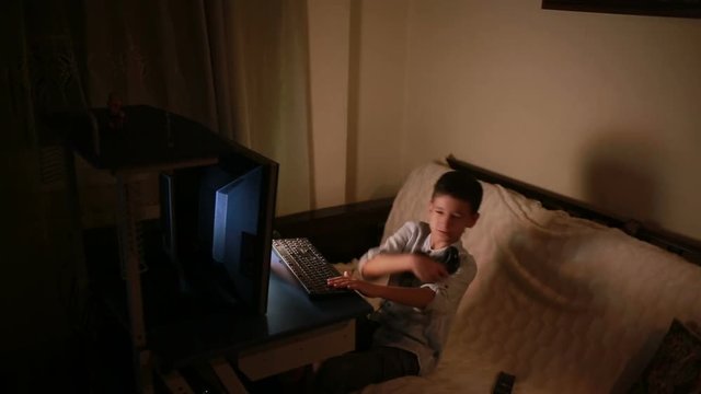 Teen boy plays games on the computer at night. Online Games