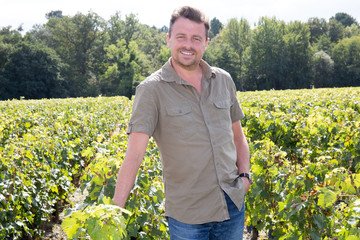 Handsome happy man smiling at camera in the grape fields