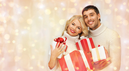happy couple in sweaters holding christmas gifts