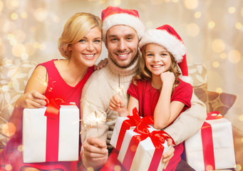 smiling family holding gift boxes and sparkles