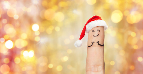 close up of one finger in santa hat over lights