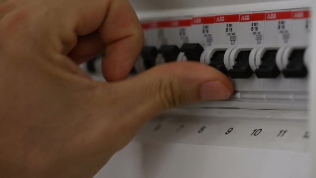 Close-up Of A Person's Hand Switching On Fuse Board