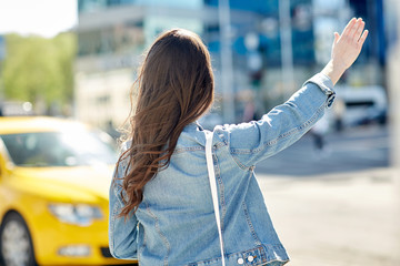 young woman or girl catching taxi on city street