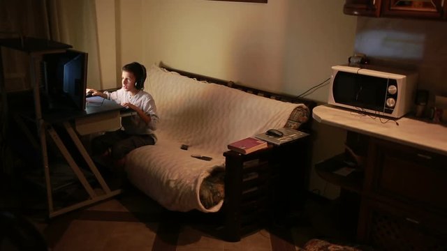 Teen boy plays games on the computer at night. Online Games