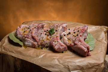 Raw pork ribs with spices, salt and rosemary on dark wooden background