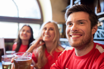 fans or friends watching football at sport bar